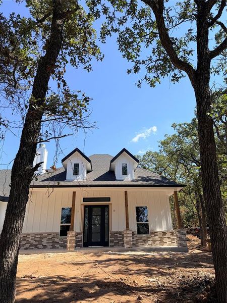 Modern farmhouse style home with covered porch, brick siding, and board and batten siding