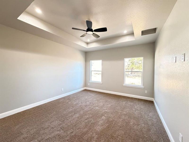 Spare room featuring a tray ceiling, ceiling fan, and dark carpet Spare room featuring a tray ceiling, ceiling fan, and dark carpet