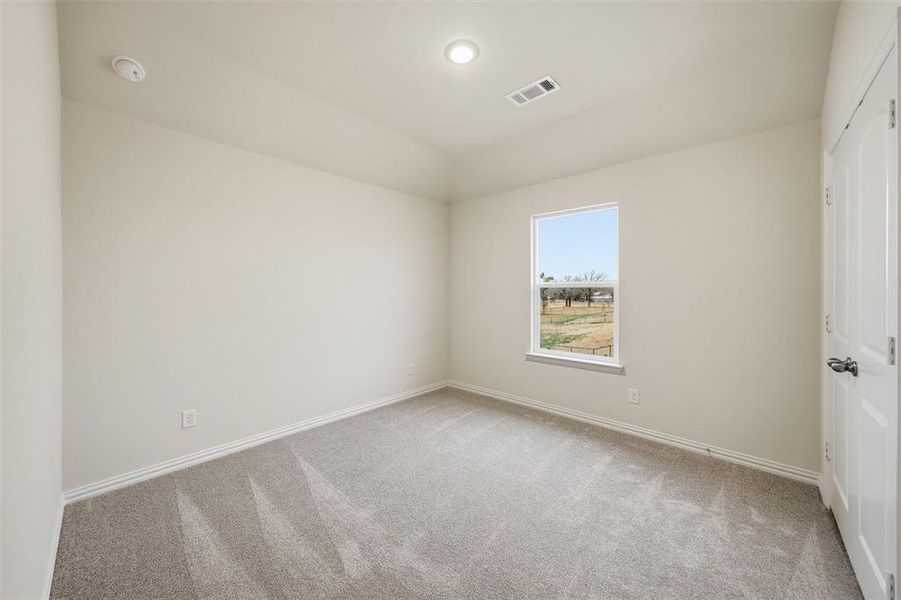 Empty room featuring light colored carpet and lofted ceiling