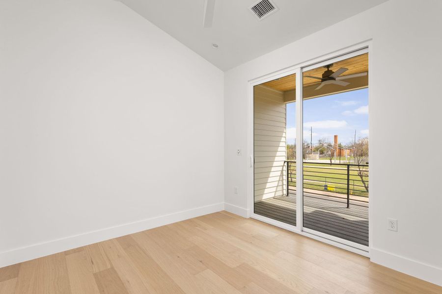 Empty room featuring light wood-style flooring, a ceiling fan, and vaulted ceiling
