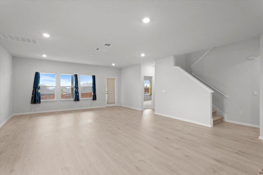 Spacious room featuring light wood-finish flooring, recessed lighting, and multiple windows