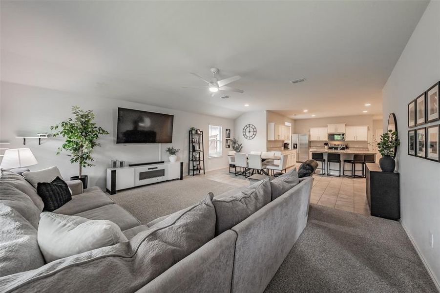 Expansive open-concept living area featuring carpet flooring, white walls, and a ceiling fan