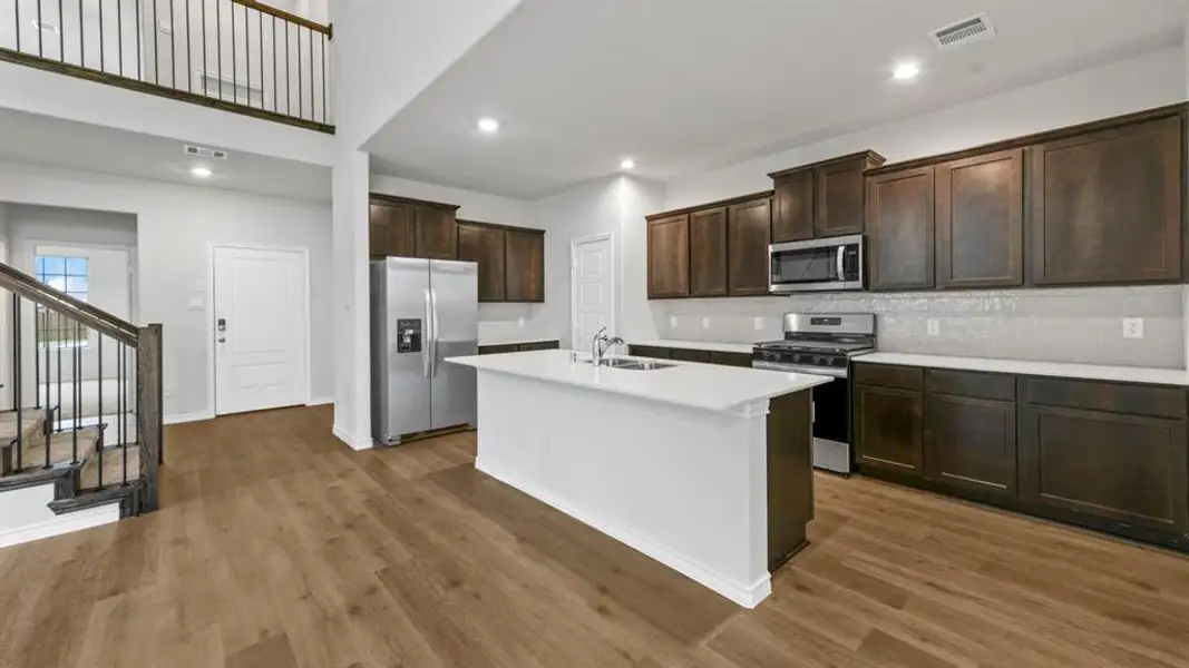 Kitchen with stainless steel appliances, dark wood finish cabinetry, an island with sink, recessed lighting, and dark wood finished floors Kitchen with stainless steel appliances, dark wood finish cabinetry, an island with sink, recessed lighting, and dark wood finished floors