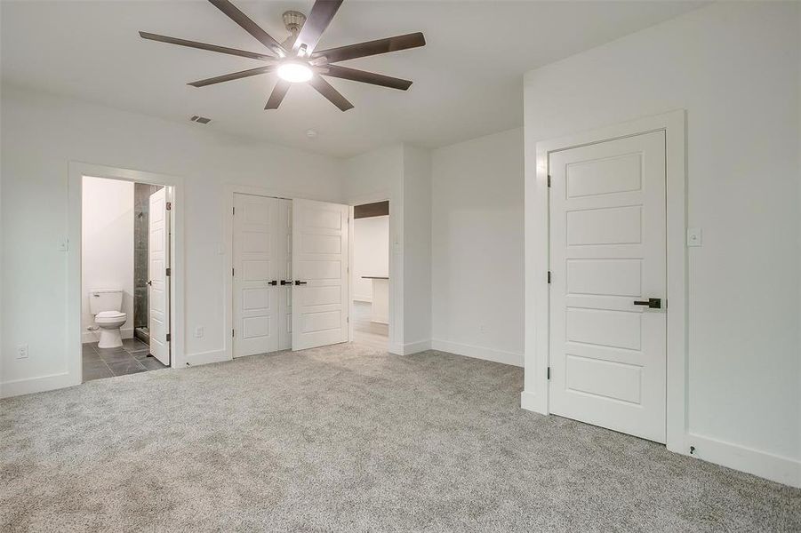 Unfurnished bedroom with carpet flooring, connected bathroom, and ceiling fan