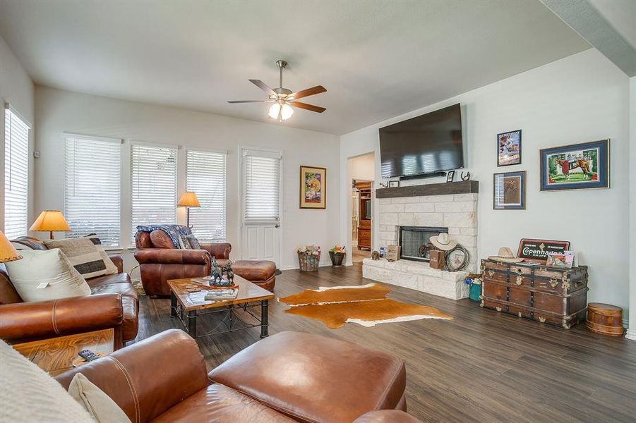 Living area with wood finished floors, a fireplace, healthy amount of natural light, and ceiling fan Living area with wood finished floors, a fireplace, healthy amount of natural light, and ceiling fan