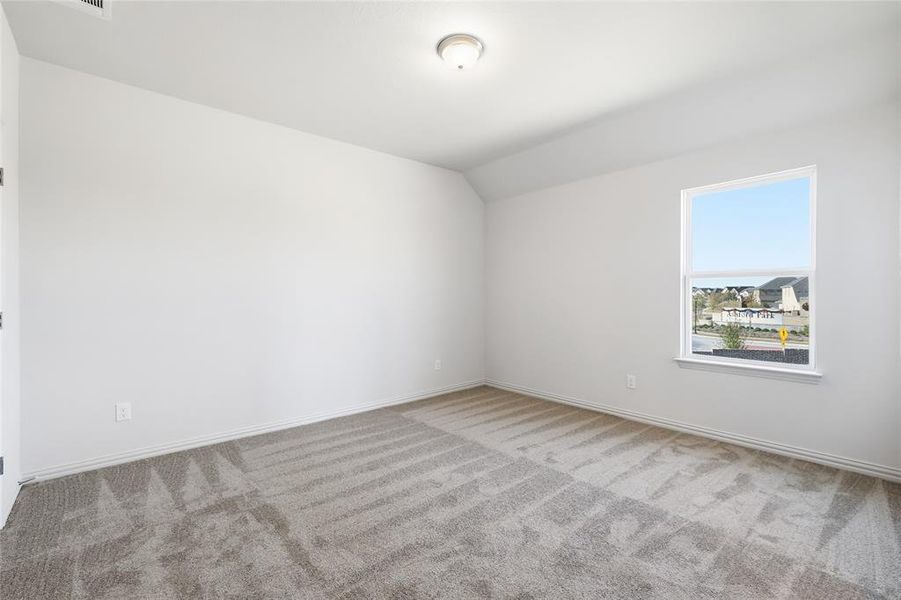 Spare room with vaulted ceiling and carpet