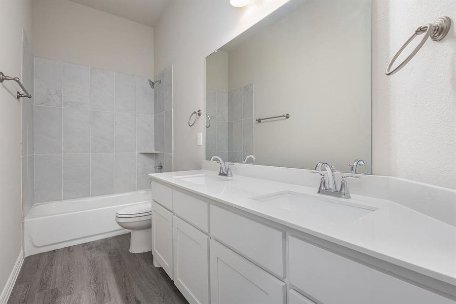 Full bathroom featuring hardwood / wood-style floors, vanity, toilet, and tiled shower / bath combo