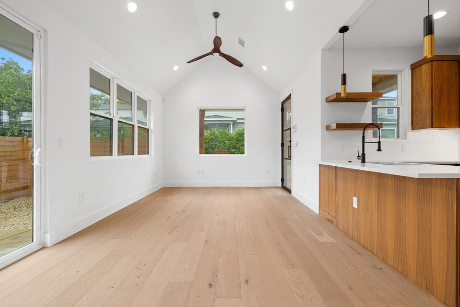 Unfurnished living room with plenty of natural light, light wood-style floors, recessed lighting, a ceiling fan, and vaulted ceiling Unfurnished living room with plenty of natural light, light wood-style floors, recessed lighting, a ceiling fan, and vaulted ceiling