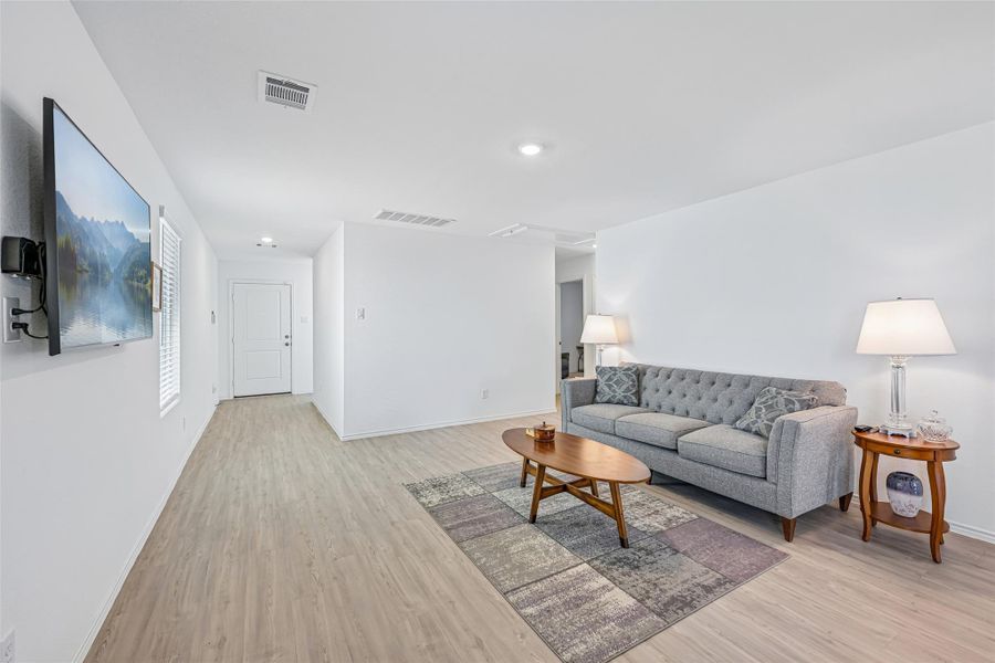 Open-concept living space featuring wood-finish flooring, recessed lighting, and white walls throughout Open-concept living space featuring wood-finish flooring, recessed lighting, and white walls throughout