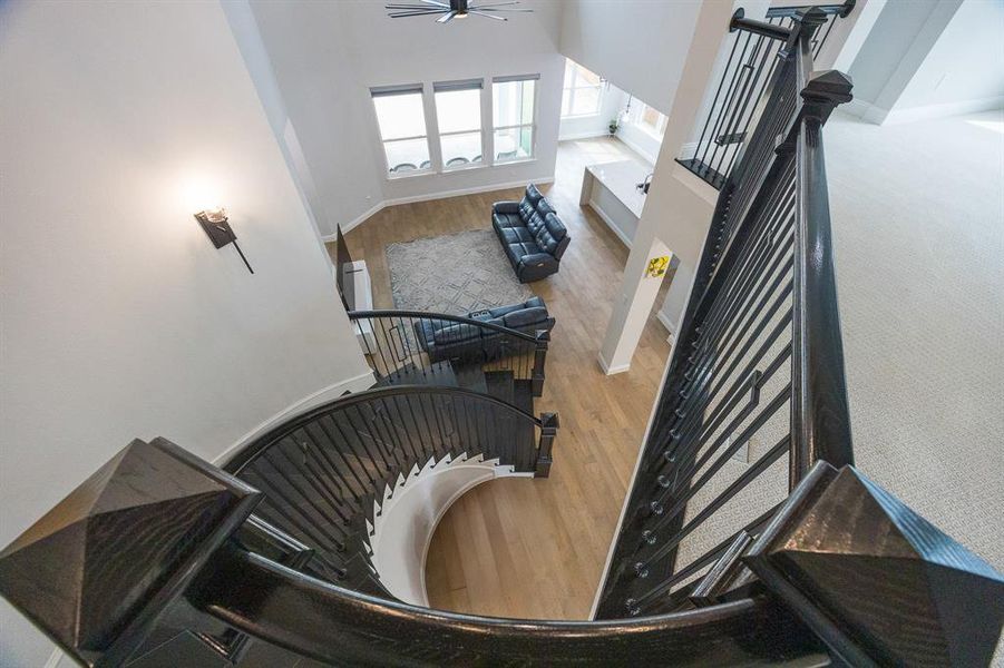 Stairs featuring baseboards, a ceiling fan, a towering ceiling, and wood finished floors