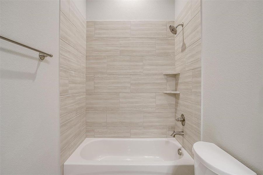 Bathroom featuring tiled shower / bath and toilet