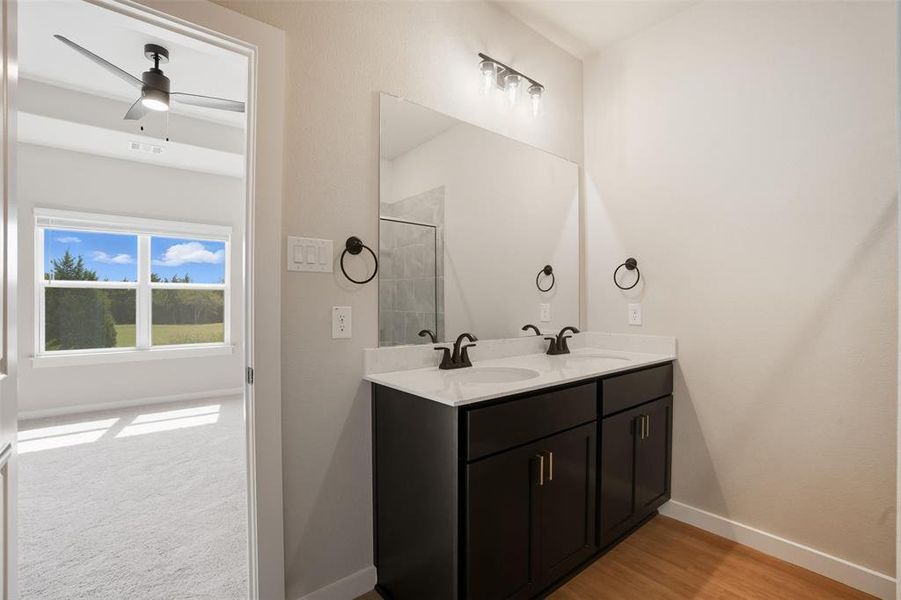 Full bathroom with double vanity, ceiling fan, a stall shower, and light wood finished floors Full bathroom with double vanity, ceiling fan, a stall shower, and light wood finished floors