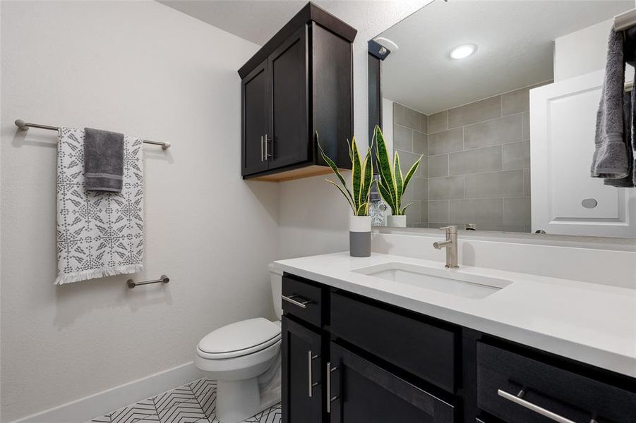 Against the backdrop of neutral tones, the eye is drawn to the intricate patterns and bold design of the floor in the guest bath.