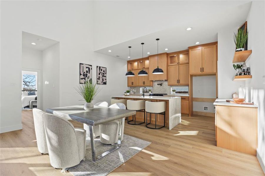 Dining space featuring light wood-type flooring, recessed lighting, and a high ceiling