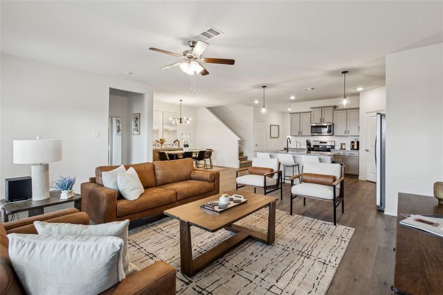 Living area with recessed lighting, visible vents, dark wood-type flooring, stairs, and ceiling fan with notable chandelier