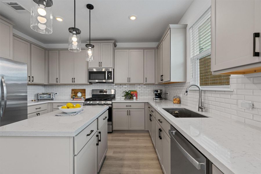 Kitchen featuring stainless steel appliances, gray cabinets, center island, and recessed lighting
