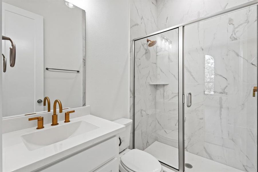 Bathroom with a marble finish shower and vanity