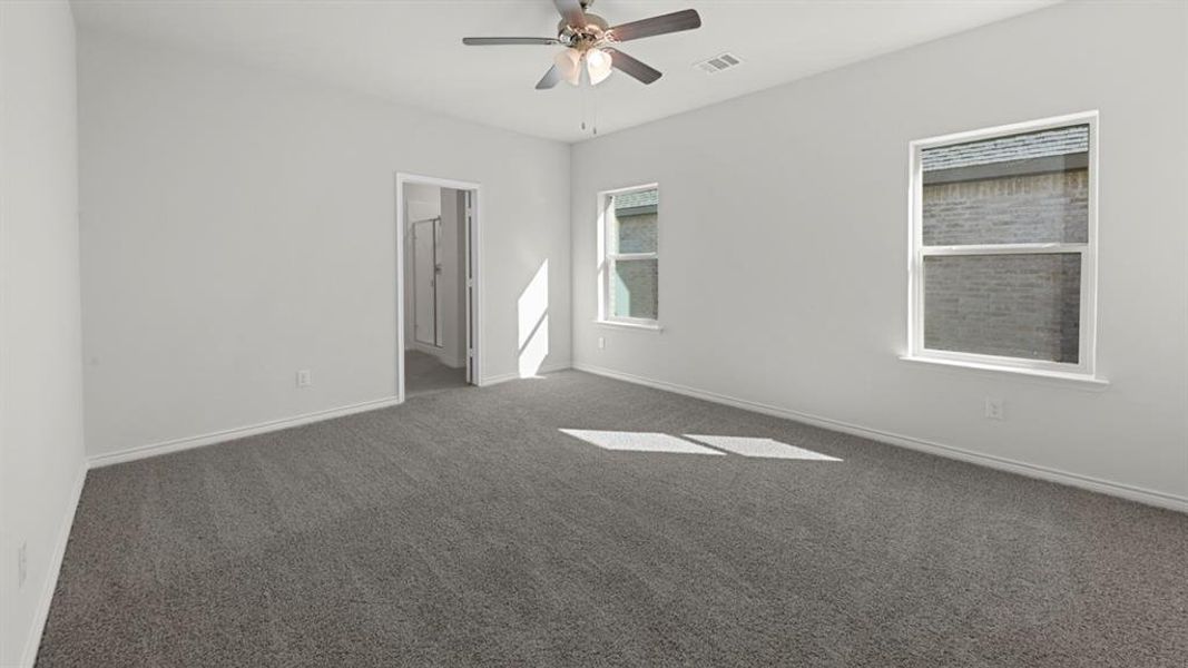 Spacious interior room featuring plush gray carpeting, white walls, and a ceiling fan with integrated lighting Spacious interior room featuring plush gray carpeting, white walls, and a ceiling fan with integrated lighting