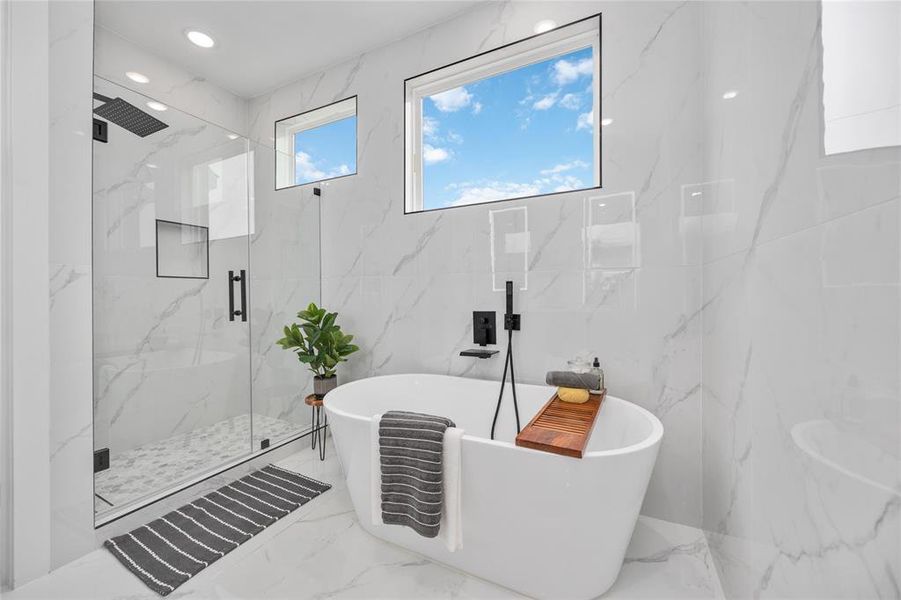 Luxurious freestanding soaking tub and glass enclosed walk-in shower