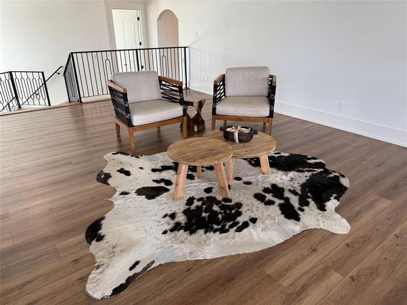 Sitting room featuring an upstairs landing, arched walkways, and wood finished floors Sitting room featuring an upstairs landing, arched walkways, and wood finished floors