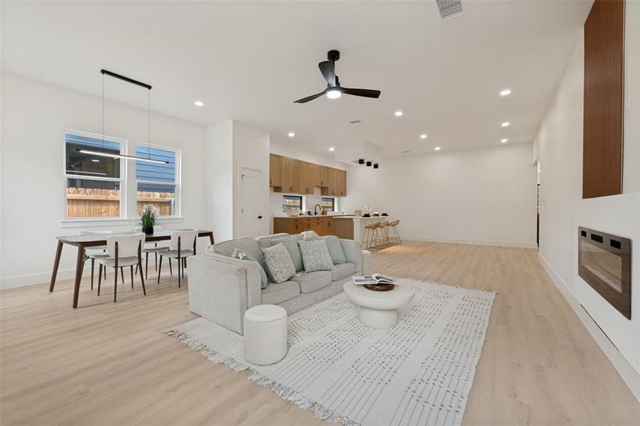 Open concept living area with light wood-finish flooring, recessed lighting, and a modern ceiling fan