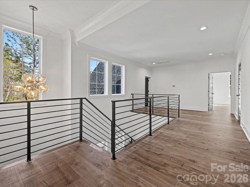 Spacious upper-level landing with modern railing, abundant natural light, and versatile space ideal for a loft, office, or additional living area.