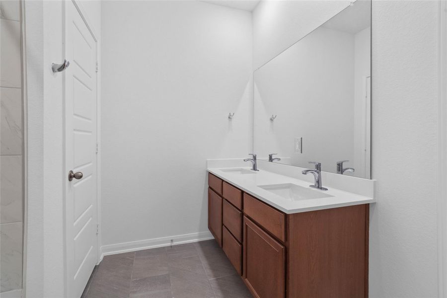 This stunning primary bathroom is truly move-in ready! It features stained cabinetry with light countertops, dual sinks, a large mirror, high ceilings, custom paint, and sleek modern finishes throughout.