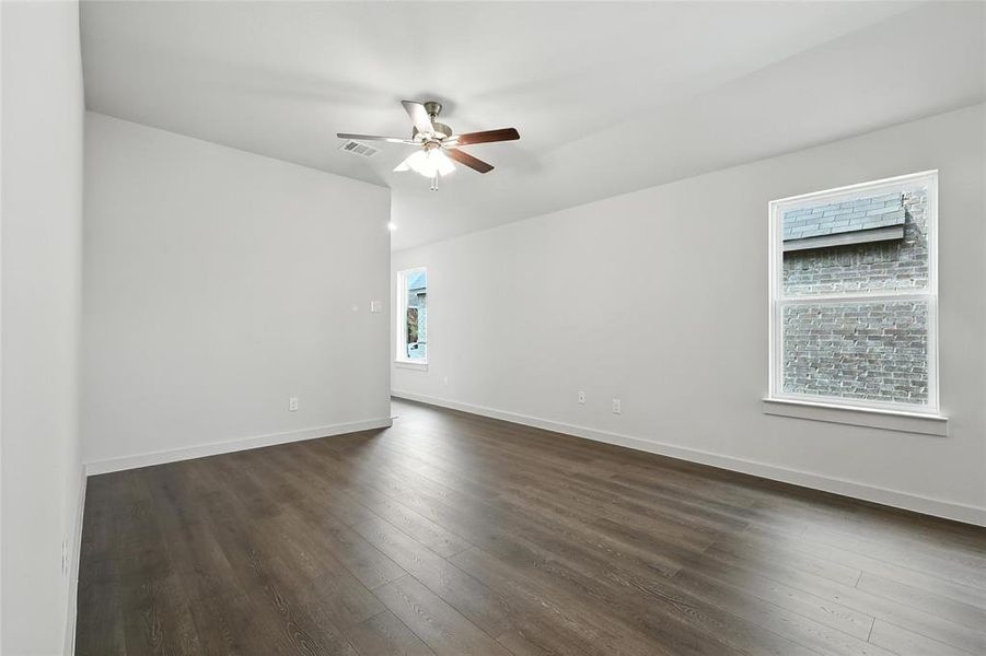 Empty room featuring ceiling fan and dark wood-style floors Empty room featuring ceiling fan and dark wood-style floors