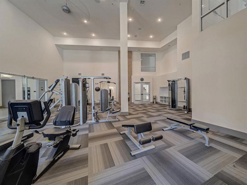 Exercise room featuring a towering ceiling and recessed lighting