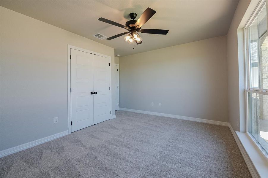 Unfurnished bedroom with a ceiling fan, carpet floors, and a closet