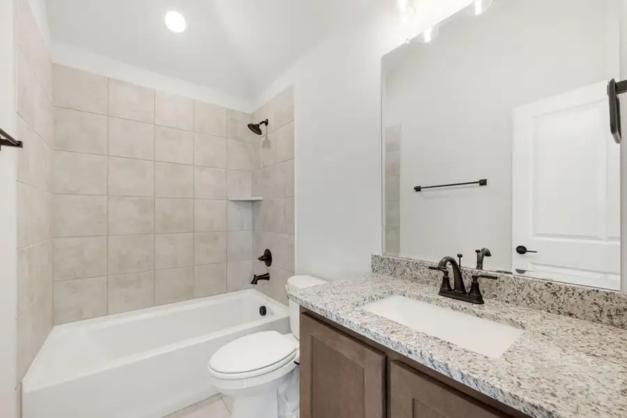 Bathroom with tiled tub-shower combo, granite vanity countertop, and dark bronze fixtures Bathroom with tiled tub-shower combo, granite vanity countertop, and dark bronze fixtures