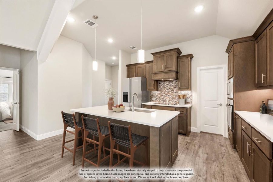 Kitchen with dark wood cabinets, large island with seating, tile backsplash, and stainless steel appliances