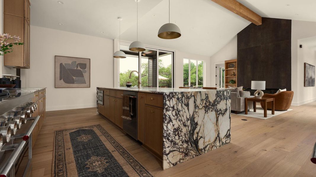 An inviting kitchen with soaring vaulted ceilings and a waterfall-edge marble island connects seamlessly to a living area. An inviting kitchen with soaring vaulted ceilings and a waterfall-edge marble island connects seamlessly to a living area.