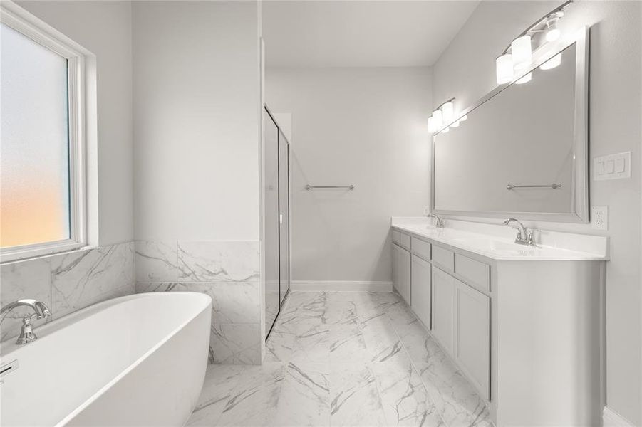 Full bath with marble look tile flooring, a freestanding bath, double vanity, and a shower