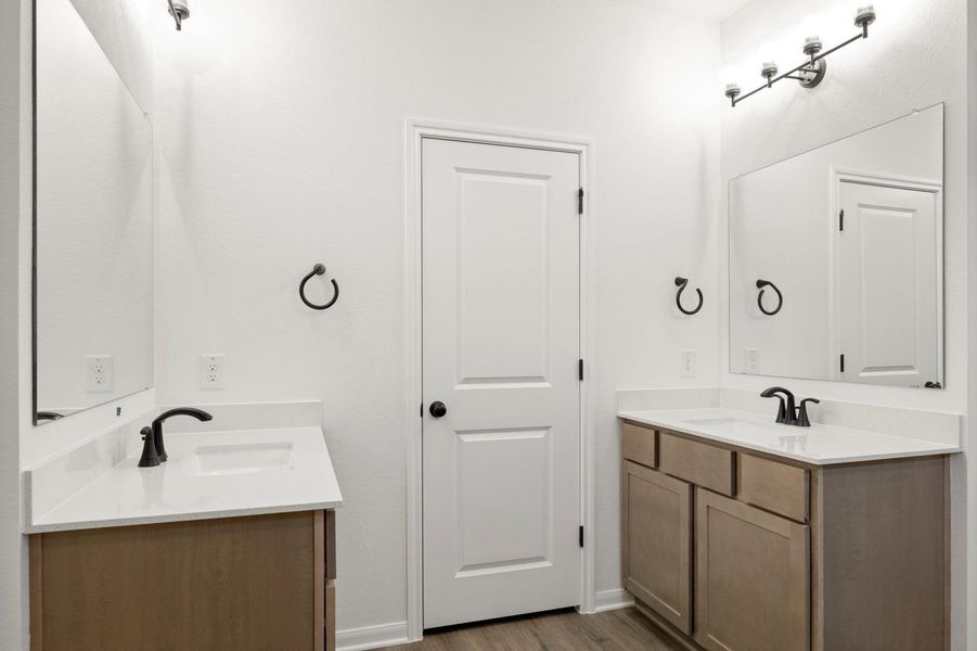 Full bath with two vanities and dark wood-style floors