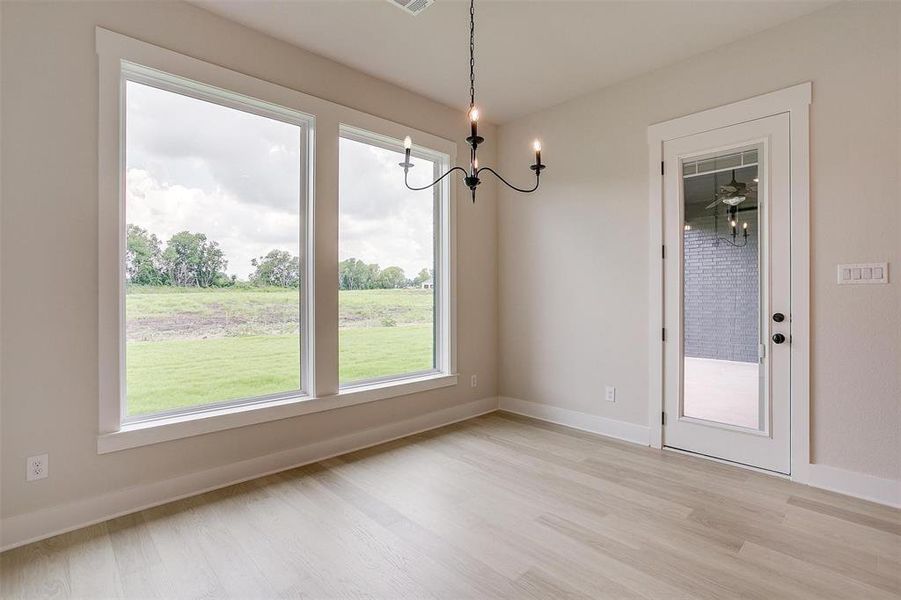 Spare room with a chandelier and light hardwood / wood-style flooring