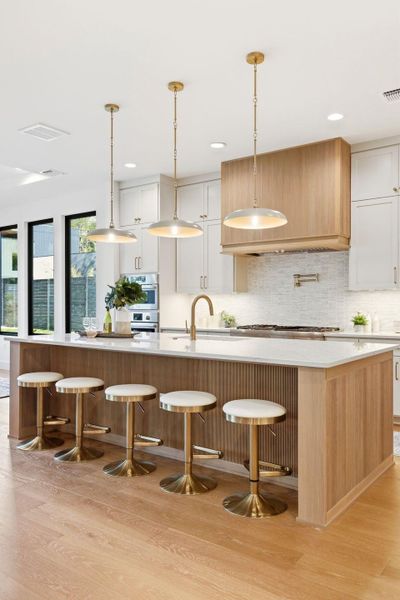 Kitchen featuring a large island, a breakfast bar, hanging light fixtures, and light wood-style flooring Kitchen featuring a large island, a breakfast bar, hanging light fixtures, and light wood-style flooring