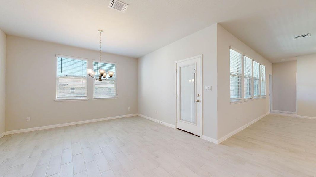 Unfurnished dining area featuring a chandelier, plenty of natural light, and light wood-style flooring