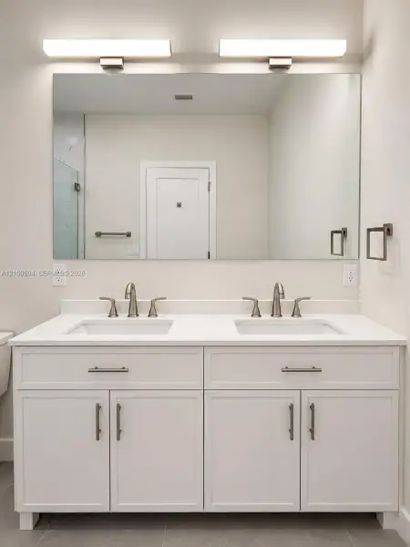 Double vanity featuring a quartz countertop, dual under-mount rectangular sinks, brushed nickel hardware, and two integrated wall-mounted light fixtures