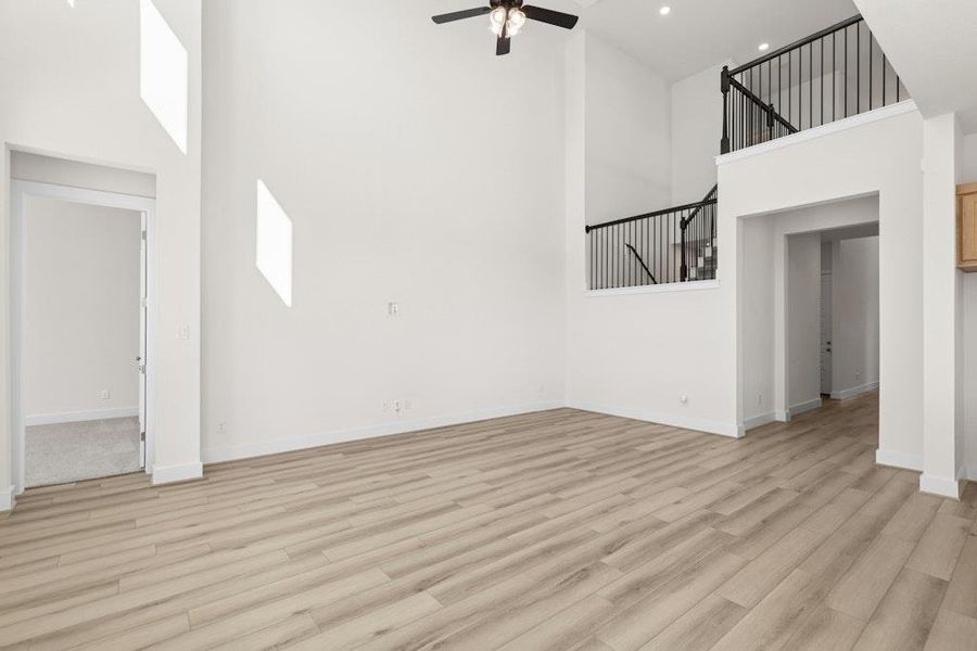 Unfurnished living room featuring a towering ceiling, light wood-style flooring, ceiling fan, and recessed lighting Unfurnished living room featuring a towering ceiling, light wood-style flooring, ceiling fan, and recessed lighting