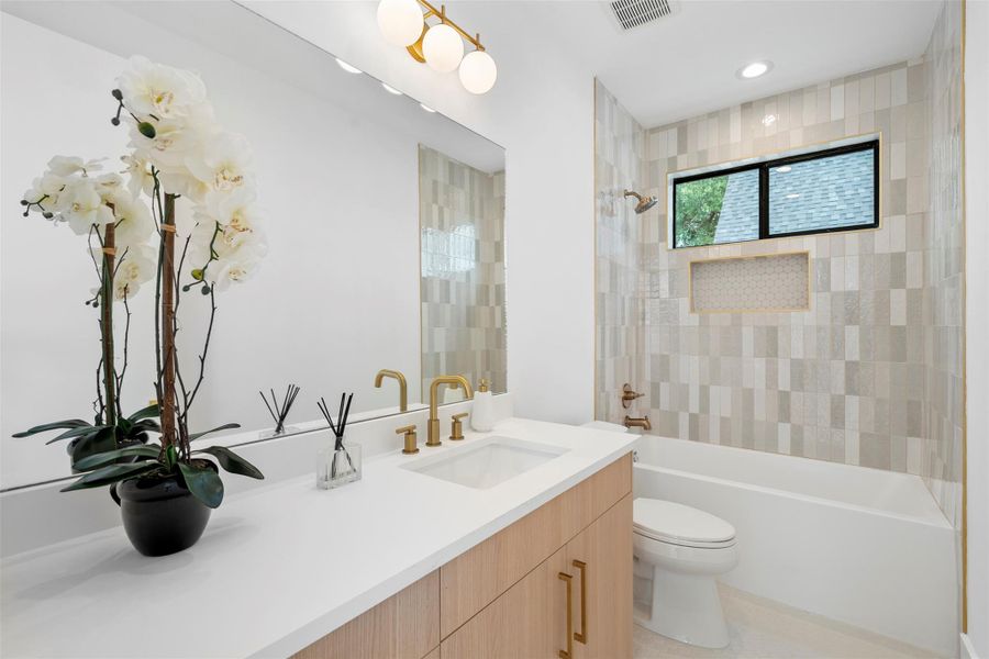 Bathroom featuring a white bathtub, a tiled shower wall with a built-in niche, and a window above the shower