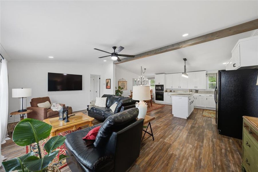 Open-concept living area featuring wood-finish flooring, vaulted ceilings with exposed beam details, and recessed lighting