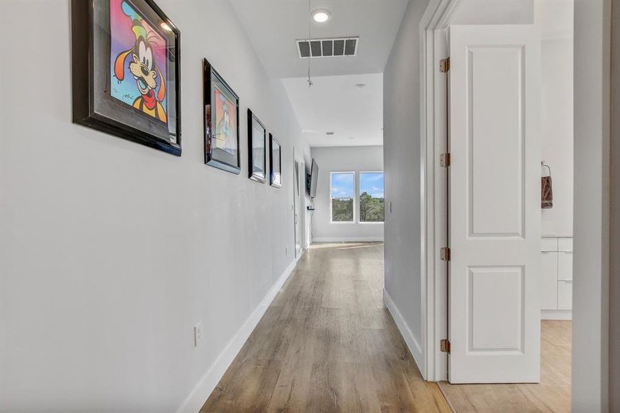 Hallway  entrance with with luxury vinyl finished floors and recessed lighting to the main bedroom with sliding glass doors to the balcony