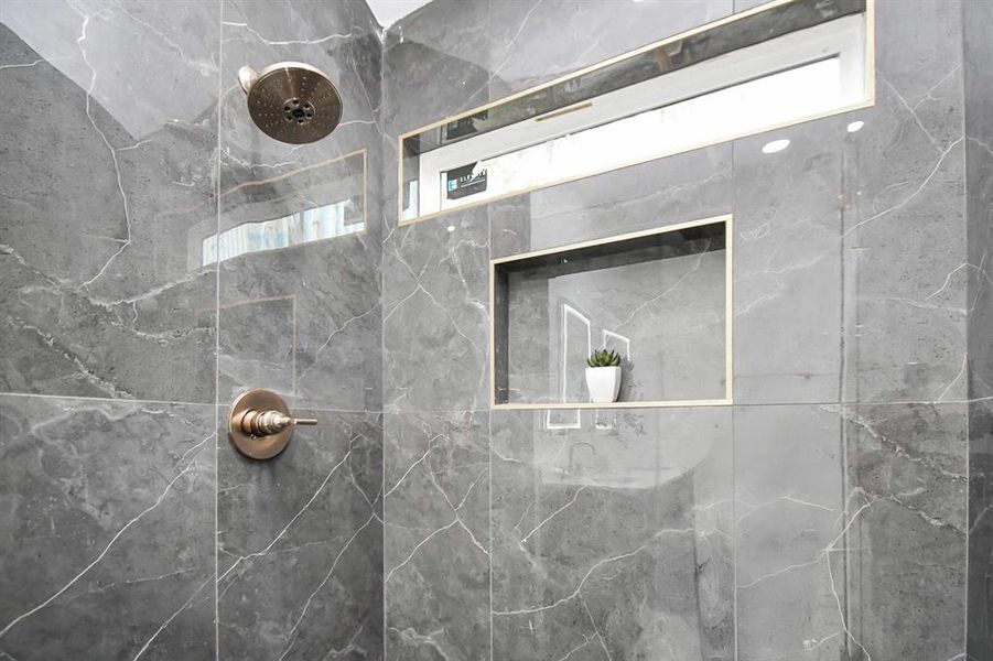 This is a modern bathroom featuring a sleek double vanity with gold fixtures, backlit mirrors, and a spacious linen closet to the left. The room is finished with white walls and a light wood floor.