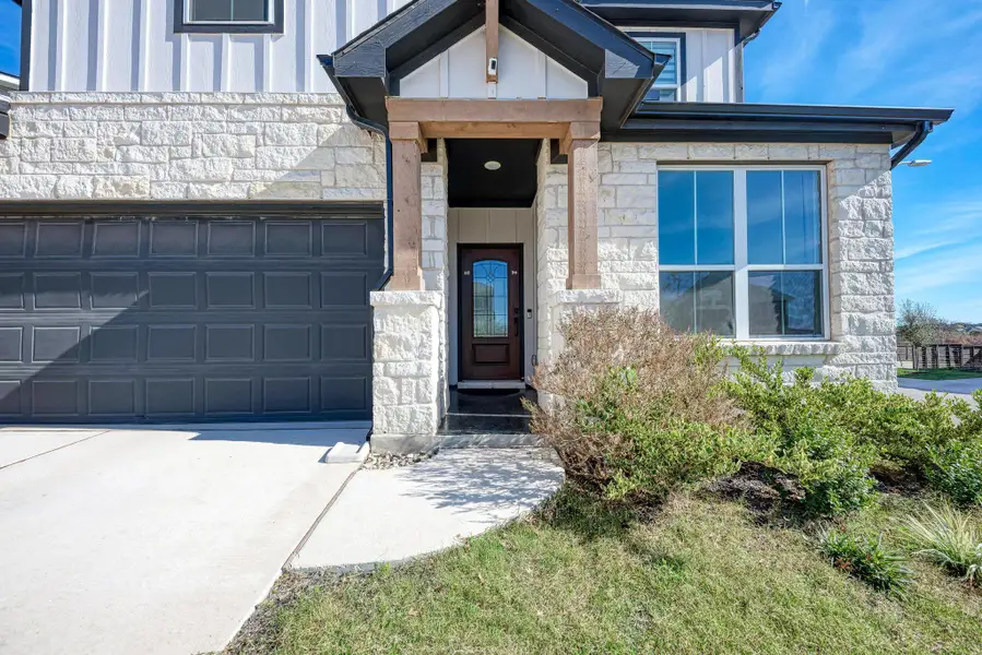 View of exterior entry featuring stone siding, board and batten siding, and concrete driveway