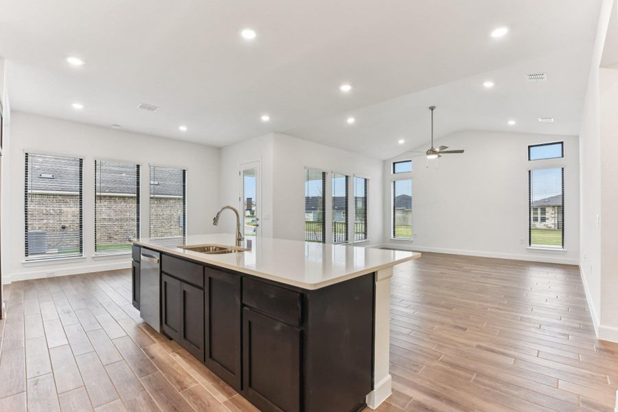 Kitchen with open floor plan, recessed lighting, wood tiled floors, a center island with sink, and light stone countertops Kitchen with open floor plan, recessed lighting, wood tiled floors, a center island with sink, and light stone countertops