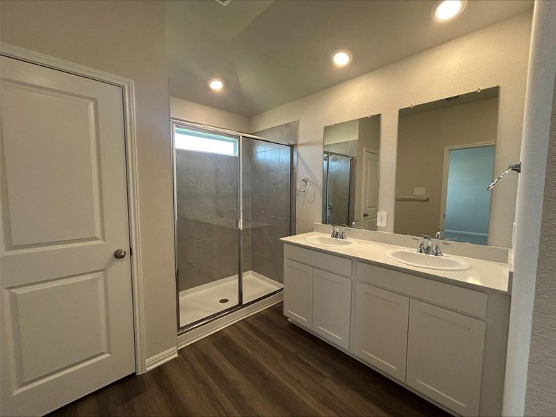 Bathroom with a shower stall, double vanity, dark wood-style floors, lofted ceiling, and recessed lighting Bathroom with a shower stall, double vanity, dark wood-style floors, lofted ceiling, and recessed lighting