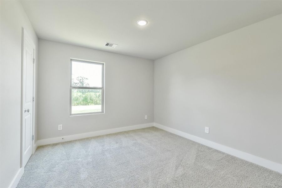 Secondary bedroom with window overlooking the side yard of the corner lot.
