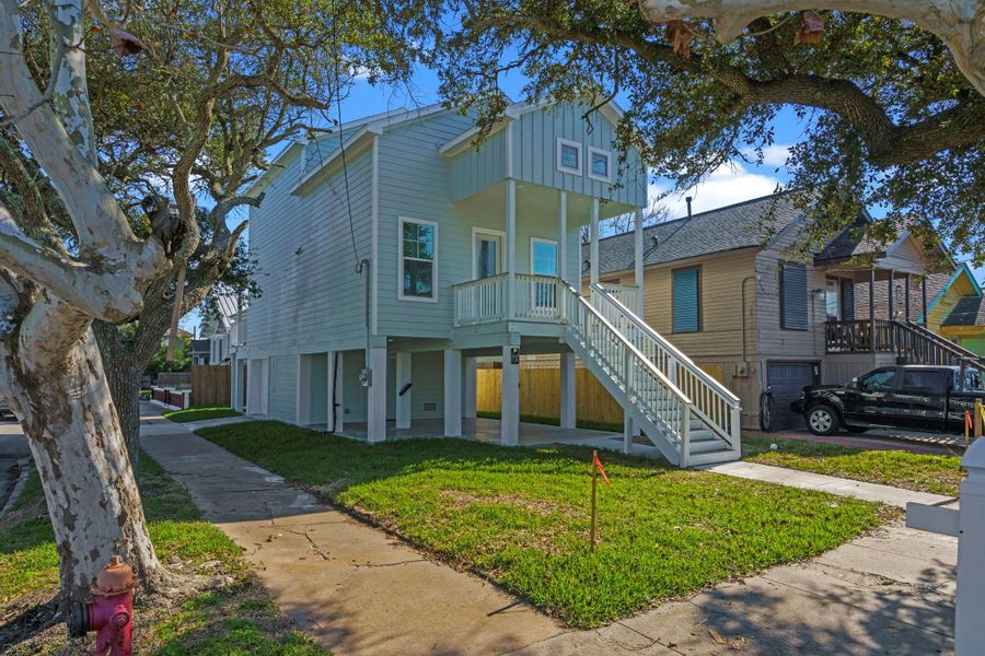This elevated, light green home features a charming front porch and staircase, set in a suburban neighborhood. Surrounded by mature trees, it offers a spacious driveway and appears well-maintained, perfect for comfortable living. This elevated, light green home features a charming front porch and staircase, set in a suburban neighborhood. Surrounded by mature trees, it offers a spacious driveway and appears well-maintained, perfect for comfortable living.