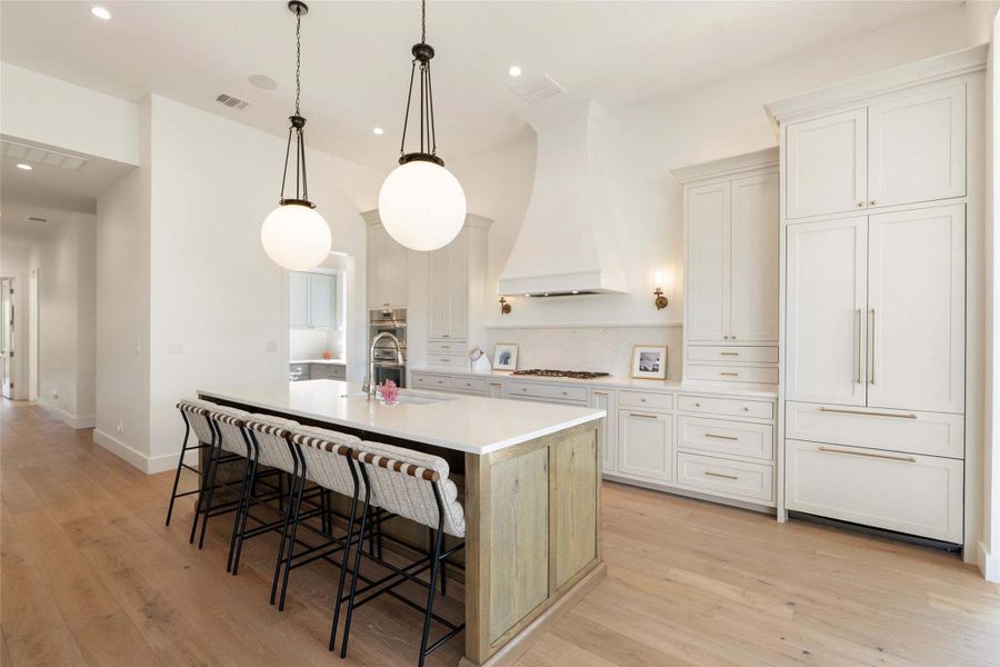 An inviting kitchen showcasing a spacious island with seating, pendant lighting, and state-of-the-art built-in appliances. An inviting kitchen showcasing a spacious island with seating, pendant lighting, and state-of-the-art built-in appliances.